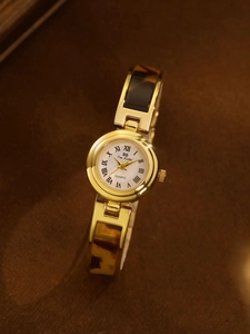 Detail of gold quartz watch with white mother-of-pearl dial and leopard print band