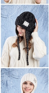 Detail of warm winter knit beanies with earflaps and tie strings in black and cream colors