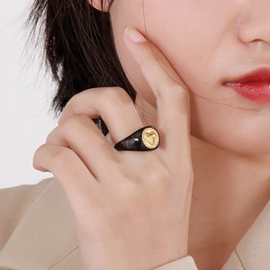 Detail of a vintage 18K gold heart emblem on a wide black resin band worn by a model