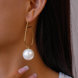 Orecchini geometrici dorati con grande perla bianca indossati da una modella reale
