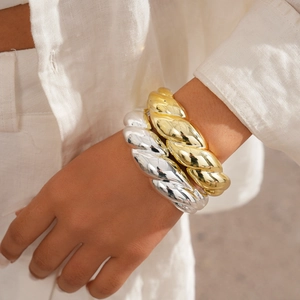 Chunky twisted gold and silver rope bracelets layered on a model's wrist for a trendy look