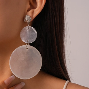 Exaggerated silver shell-inspired ruffled drop earrings for women on a beige background