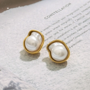 Detailed view of gold pearl earrings featuring irregular white pearls on textured paper