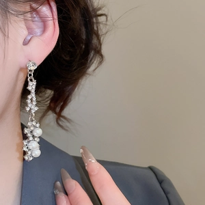 Detailed view of elegant silver floral earrings with sparkling rhinestones and pearls on model