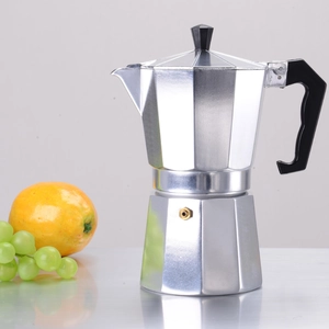 Detailed view of silver octagonal aluminum moka pot with fresh fruit props on reflective surface