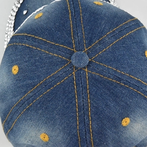 Top view of blue denim baseball cap with yellow stitching and silver rhinestone brim decor