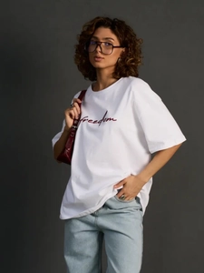 Oversized λευκό βαμβακερό T-shirt με κόκκινη επιγραφή freedom σε μινιμαλιστικό φόντο