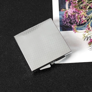 Detail view of square silver metal makeup mirror with intricate textured pattern design