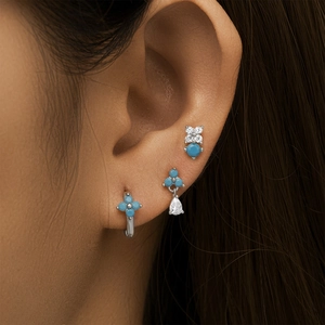 Detailed view of silver petal and waterdrop earrings with turquoise and zircon on model
