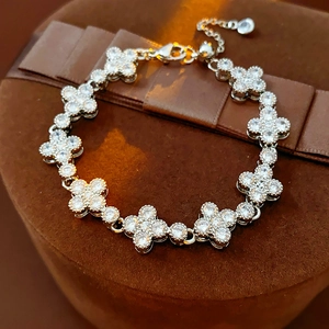 Close-up of silver clover bracelet with inlaid zircons resting on a luxury gift box