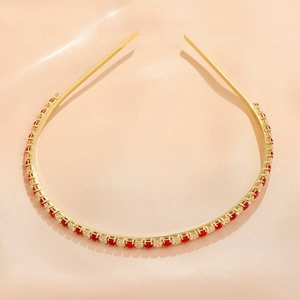 Close-up of golden metal headband with red and clear square crystals on silk fabric