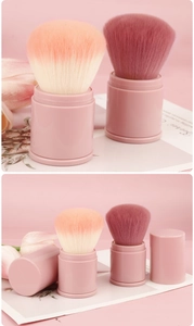 Detail of pink retractable makeup brush showing fluffy peach and rose bristles with cap