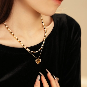 Detail of double-layer necklace with heart-shaped tiger eye pendant on a gold chain
