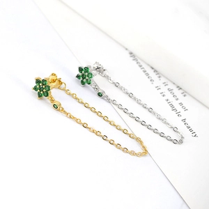 Macro shot of tassel chain earrings featuring green zircon flower studs in gold and silver