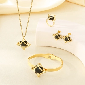 Detail shot of four-piece gold jewelry set with black stones on soft beige fabric
