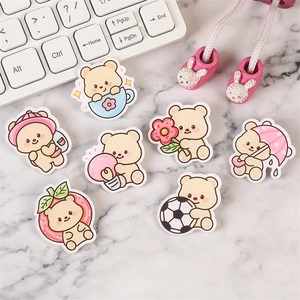 Cute Korean style yellow bear acrylic badges in seven playful poses on marble