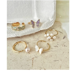 Close-up of assorted vintage gold rings featuring pearls, shell butterflies and gems