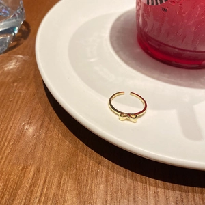 Close-up of golden bow-knot open ring placed on a white porcelain plate