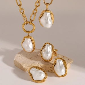 Golden baroque pearl jewelry set with necklace, ring and earrings on stone background