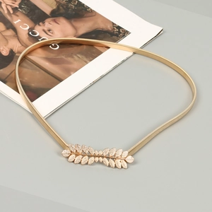 Close-up of golden elastic metal waist chain with detailed leaf-shaped buckle for dresses
