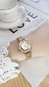 Elegant gold flower watch for women shown in a lifestyle setting with a coffee cup