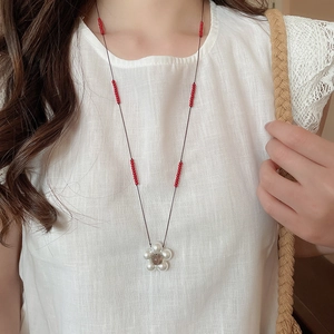 Detailed close-up of handmade resin floral pendant with red bead accents on a cord