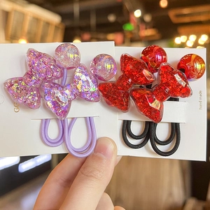 Close-up of glitter-filled resin bow hair ties in purple and red on a display card