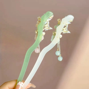 Detail of emerald green and ivory resin hair sticks with golden floral tassels