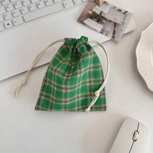 Detailed view of green plaid drawstring organizer bag on a minimalist desk workspace