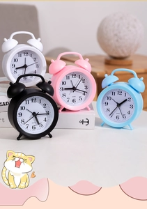 Detail view of mini quartz alarm clocks in white, pink, black, and blue pastel colors
