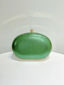 Macro detail of textured green fabric and gold rhinestone clasp on evening clutch bag
