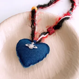 Collana a cuore in denim con logo Saturno e perle in legno su piatto ceramico