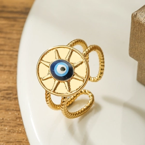 Gold-plated adjustable ring with sunburst evil eye charm on a white ceramic tray