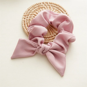 Detailed view of a pink bow hair tie on a rustic woven coaster with soft fabric texture