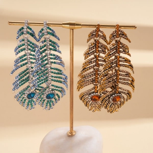 Boucles d'oreilles pendantes plumes avec strass étincelants bleus et dorés sur présentoir