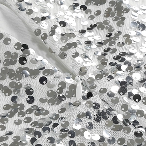 Dettaglio di paillettes argento su rete bianca con cerniera invisibile in tinta