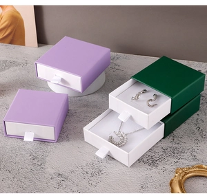 Detail of purple and green drawer jewelry boxes with ribbon pull and elegant ornaments