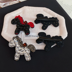 Close-up of red and white rhinestone pony hair clips with black metallic alligator base