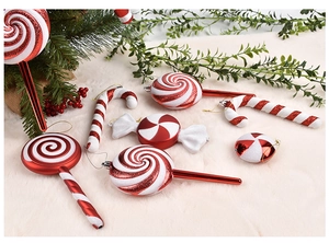 Close-up of red and white glitter candy cane ornaments on a festive pine branch