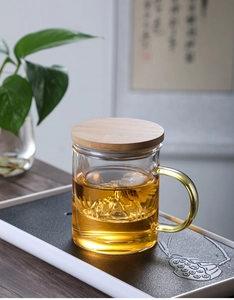 Detailed view of heat-resistant glass tea mug with wooden lid and flower tea infusion