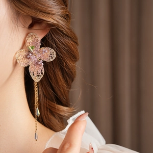 Close-up of vintage floral knit earrings with golden tassels and purple bead details