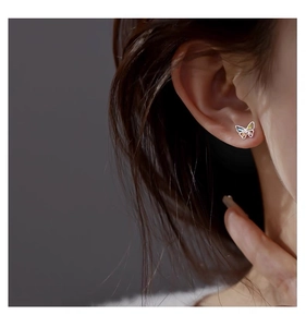Close-up of a sterling silver butterfly stud earring with colorful gems on a female ear