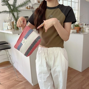 Detailed close-up of a colorful striped woven makeup bag held by a model