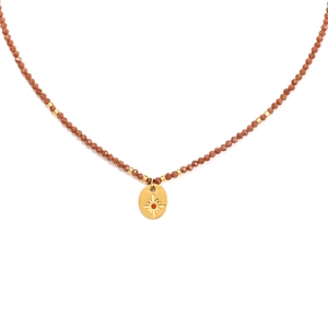 Detail of vintage sunburst pendant necklace with red brown stone beads and gold accents