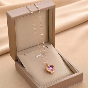 Rose gold heart pendant necklace with purple gemstones in a beige jewelry box