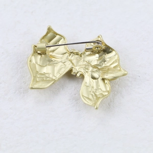 Gold bow brooch with pearl detail and safety pin closure, rear view mechanism