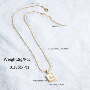 Macro detail of gold square shell pendant necklace with letter A and size specs