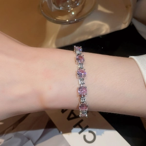 Detail of female wrist wearing silver bracelet with pink crystals and square zircons