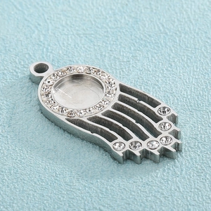 Macro shot of silver Hamsa hand charm featuring a central crystal halo and rhinestone fingers