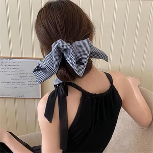 Detail of a black and white checkered bow scrunchie on a girl's soft ponytail